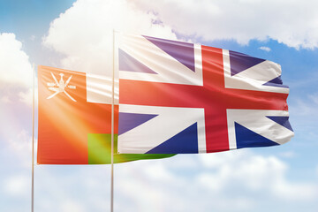 Sunny blue sky and flags of great britain and oman