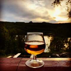 Glass with Cognac / Whiskey on Rustic Handrail at Nighttime