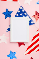 Obraz premium USA Independence Day concept. Top view vertical photo of photo frame over national flag garland and stars on isolated pastel pink background with empty space