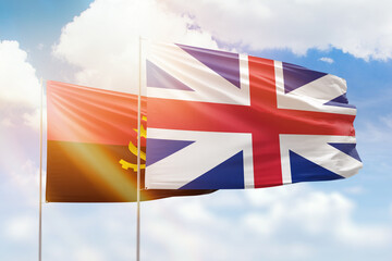 Sunny blue sky and flags of great britain and angola