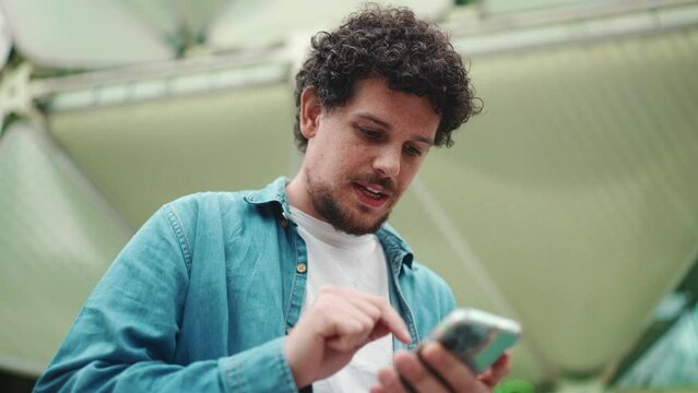 Close-up, man looks at google map on mobile phone and looks around on modern city background