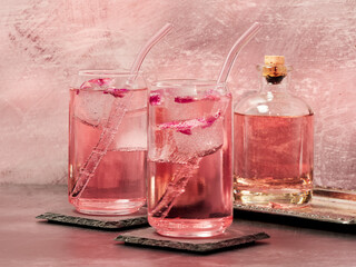 Two glasses of pink gin and rose lemonade on a pink background