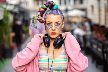 Cool funky young woman with trendy eyeglasses listening music on headphones outdoor - obrazy, fototapety, plakaty