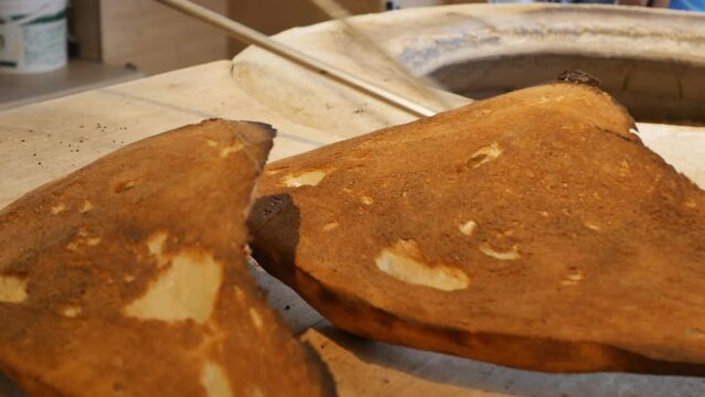 the baker takes out fresh hot national bread ojakhuri or matnakash with long metal hooks from a stone tandoor. Georgian and Armenian traditional food.