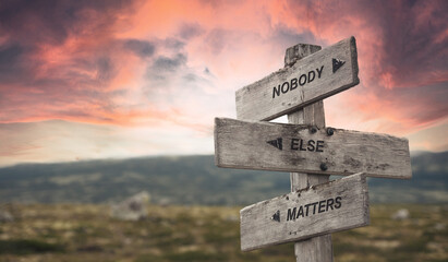 nobody else matters text quote caption on wooden signpost outdoors in nature with dramatic sunset skies. Panorama crop.