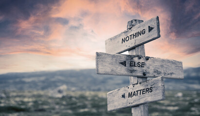 nothing else matters text quote caption on wooden signpost outdoors in nature with dramatic sunset...