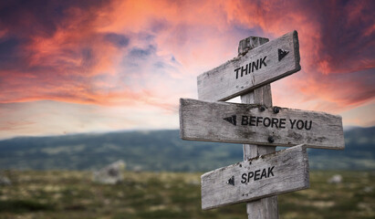 think before you speak text quote caption on wooden signpost outdoors in nature with dramatic...