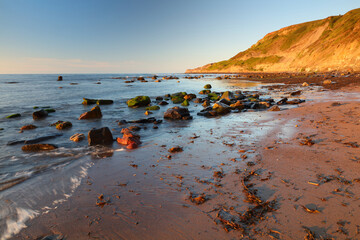 View looking out at the North Sea with rock pools and rocks in the foreground. Runswick Bay, North Yorkshire, England, UK.