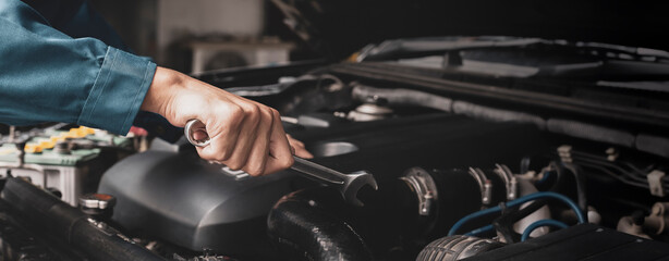 The mechanic works on the engine of the car in the garage, car repair service.