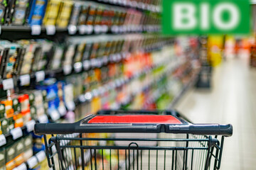 A shopping cart by a store shelf in a supermarket