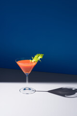 Coctel Bloody Mary decorado con hoja de apio sobre fondo azul	