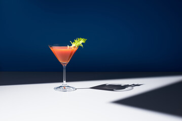 Coctel Bloody Mary decorado con hoja de apio sobre fondo azul	