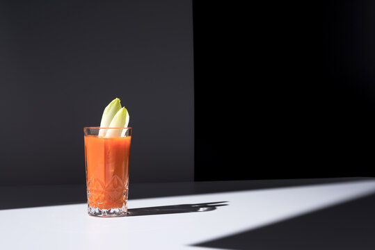 Vaso de jugo de zanahoria con hojas de endibia sobre fondo oscuro