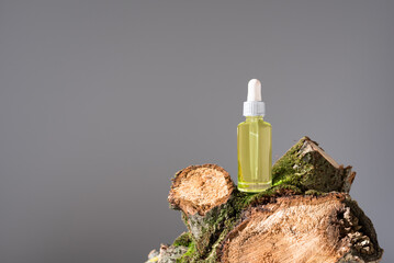 Botella de aceite esencial con cuentagotas sobre un tronco de árbol con musgo. Producto cosmético...