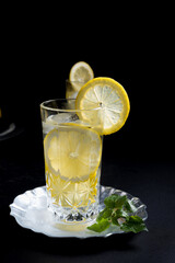 Dos vasos de refrescante zumo de limón, cóctel de frutas con rodajas de limón y hielo sobre fondo negro