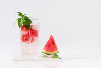 Un vaso de zumo de sandía con trozos de sandia y hielo sobre fondo claro	