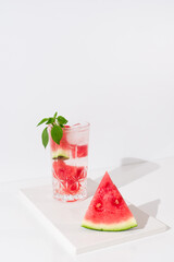Un vaso de zumo de sandía con trozos de sandia y hielo sobre fondo claro	