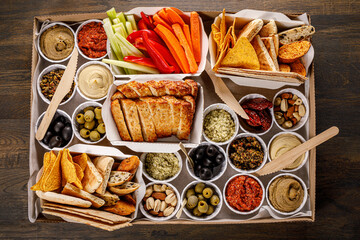 Various snacks in a cardboard box. Set of sandwiches, vegetables, sauces and canapes.