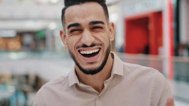Portrait funny happy Hispanic Indian bearded man Arabian guy Arab male laughing loud sincere smile looking at camera indoors smiling laugh having fun cheerful laughter reaction to humorous joke