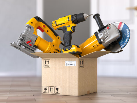 Cardboard box with elecric tools and construction equipment angle grinder, electric drill and jigsaw.  Buying online and fast delivery concept.