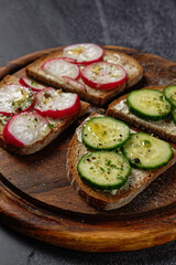 Close-up of butter sandwiches topped with cucumber and radish.