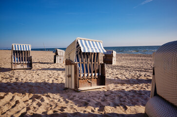 Fototapeta na wymiar Strandkorb providing shelter from sun and wind. Hooded Wicker beach chairs on a beach at the baltic sea in Bansin, Usedom, Germany
