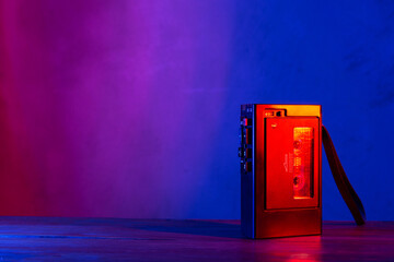Vintage cassette tape player in neon light. 80s - 90s advertisement style. Disco party nostalgy concept