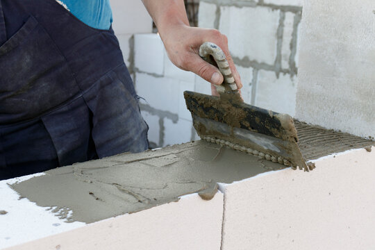 The bricklayer applies the adhesive before stealing the bricks or building blocks. The concept of building a house