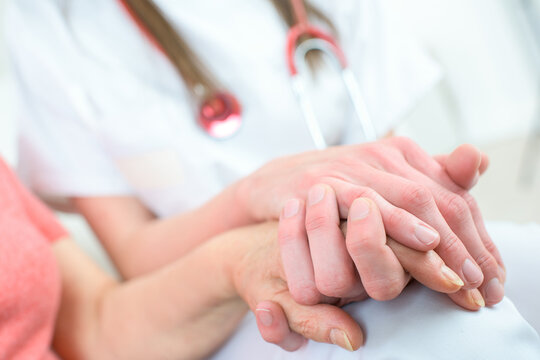 doctor holding patient hand with care giving comfort