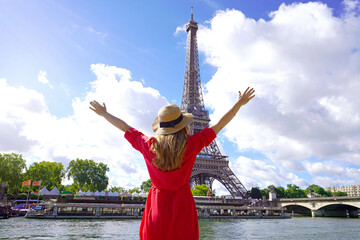 Woman traveler with hat and arms raised up on the Seine River in Paris. Back view of fashion woman...