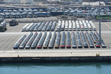 Recently discharged new cars, lorries and busses are parking in port of Valencia, ready to be drive in auto shops for costumers. In background is gas terminal. © Lucia