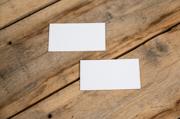 Blank business cards against a wooden background. White paper rectangles lie on top of old cracked boards. Selective focus.