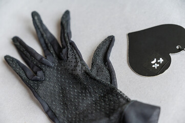 A black lace glove and a paper heart against a gray background. A sad face with crosses over the...