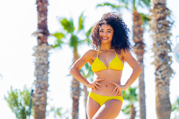 multicultural race smiling curly woman in swimming suit standing at the beach