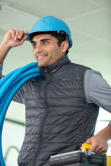 smiling male worker holding pipe at construction site