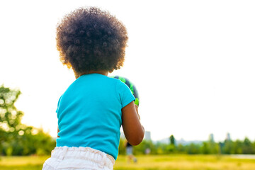 cheerful girl with afro curly hair playing with green ball like a watermelon outdoors