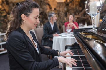 girl playing on an old piano in street cafe