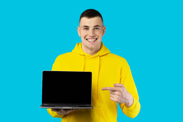 Guy Showing Laptop Empty Screen Advertising Website Over Blue Background