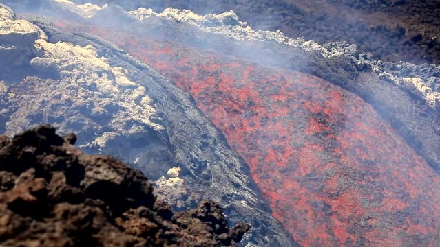 Colata di lava che scorre in primo piano sull'Etna in eruzione