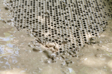 Metal sieve with round holes for cleaning dirty water from small stones