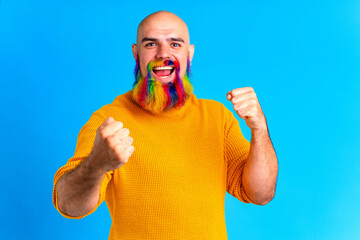 amazed man with long colorful beard feeling excited in blue studio background