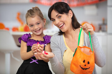 halloween dressed girl with mum holding bag of sweets