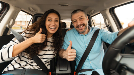 Happy Couple Sitting In New Car Gesturing Thumbs Up, Panorama