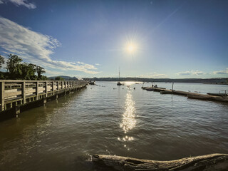 Fototapeta premium Beacon, NY - USA - June 11, 2022 Landscape view of sunset over the Scenic Hudson's Long Dock Park, located on the bank of the Hudson River at Beacon, NY. Boats and the city of Newburgh can be seen.