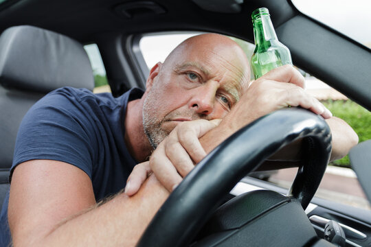drunk man slouched behind the wheel of his car
