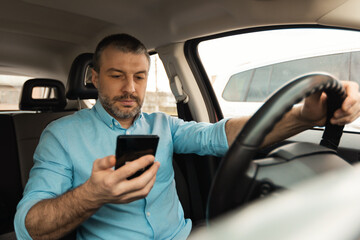 Male Driver Using Smartphone For Navigation Driving New Car