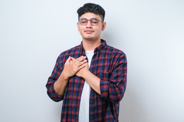 Handsome young man smiling with hands on chest with closed eyes and grateful gesture on face over white background. health concept.