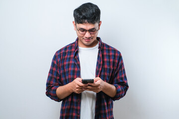 Smiling young good looking Asian man using smartphone to get in touch with family and friends