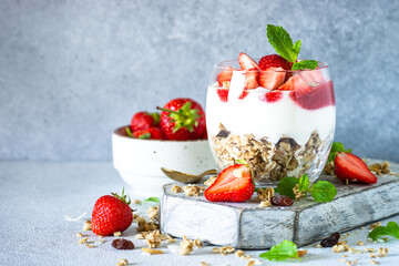 Parfait with cream or yogurt, jam and fresh strawberries in the glass jar. Close up.