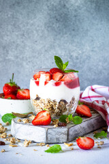 Parfait with cream or yogurt, jam and fresh strawberries in the glass jar. Close up.